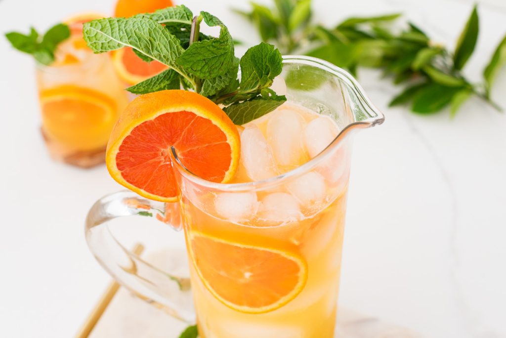 range juice mocktail in large pitcher with fresh mint and citrus slices”