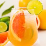 Glass of fresh paloma mocktail with slices of grapefruit and lime slice with ice