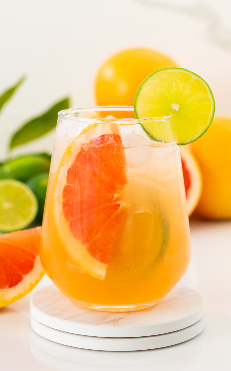 Glass of fresh paloma mocktail with slices of grapefruit and lime slice with ice