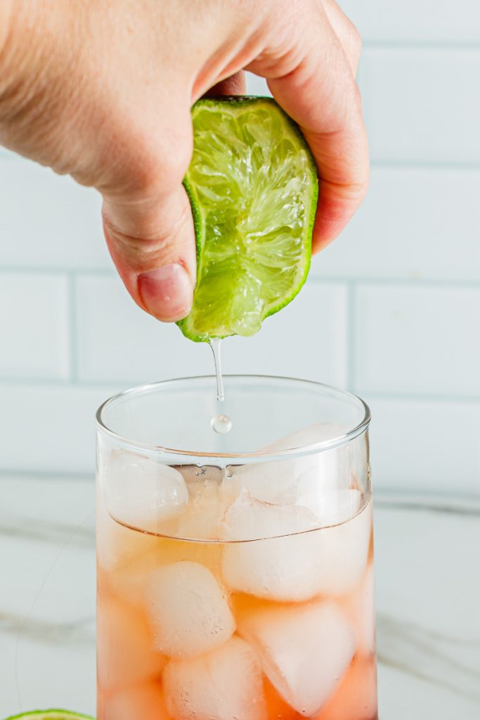 Adding fresh lime juice to a mocktail 