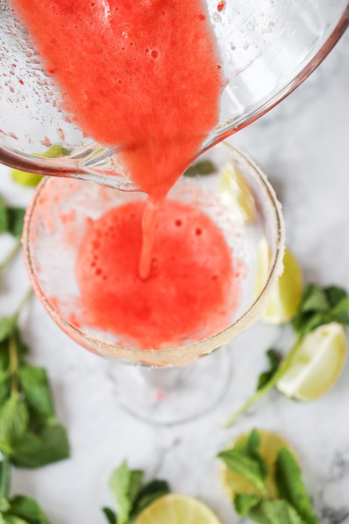 Pouring Strawberry Puree into glass to make a strawberry mojito mocktail
