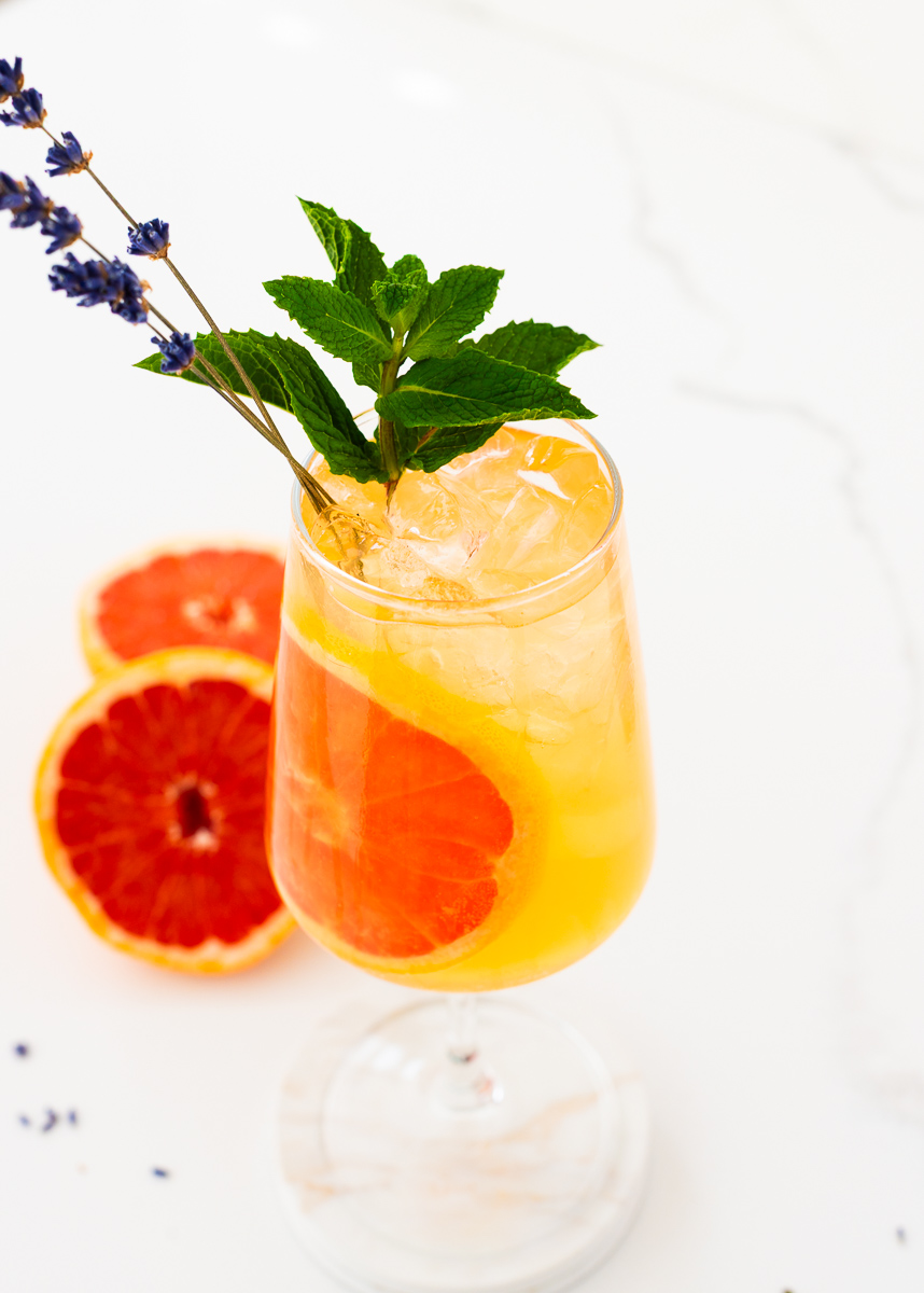 glass of grapefruit mocktail with lavender and fresh graefruits