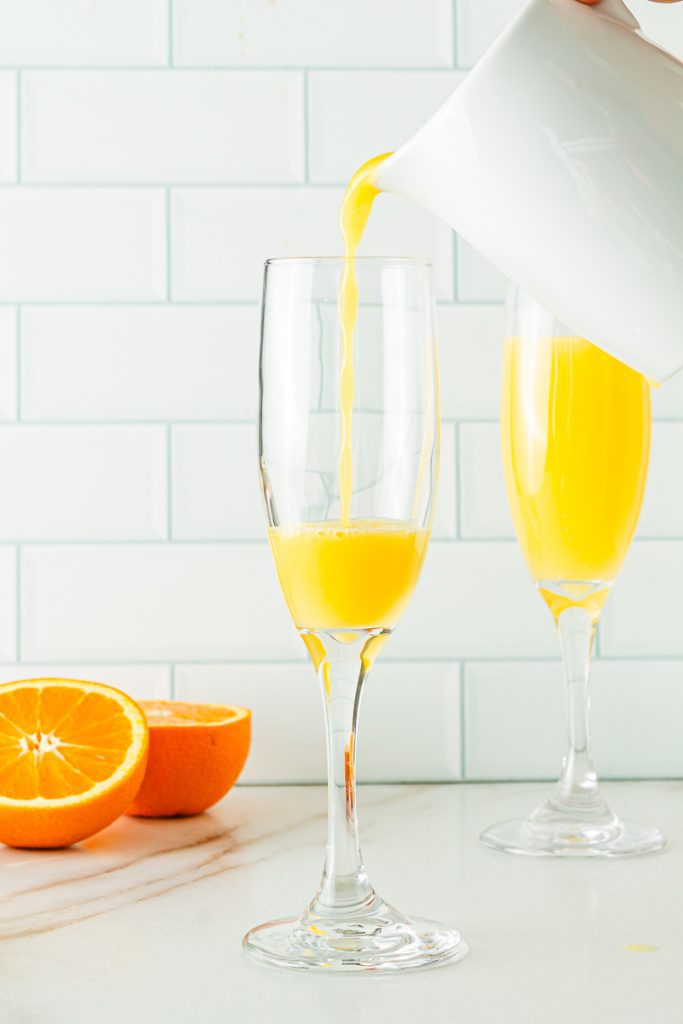 pouring orange juice in a champagne flute