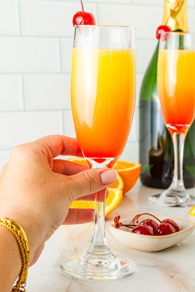 Hand holing a Non-alcoholic Tequila Sunrise Brunch Mocktail