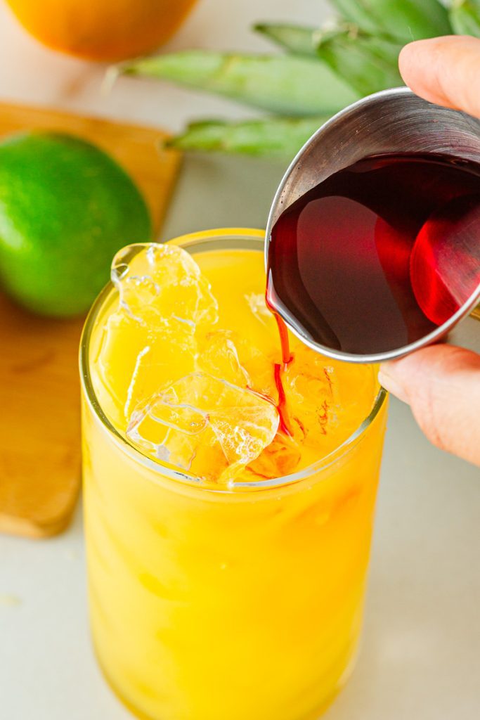 Pour grenadine into virgin tequila sunrise in a tall glass