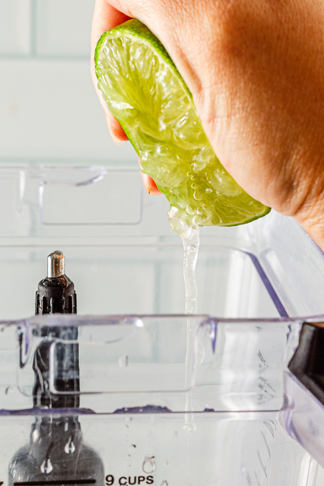 Fresh lime juice being squeezed into Mango Mocktail mixture in blender"