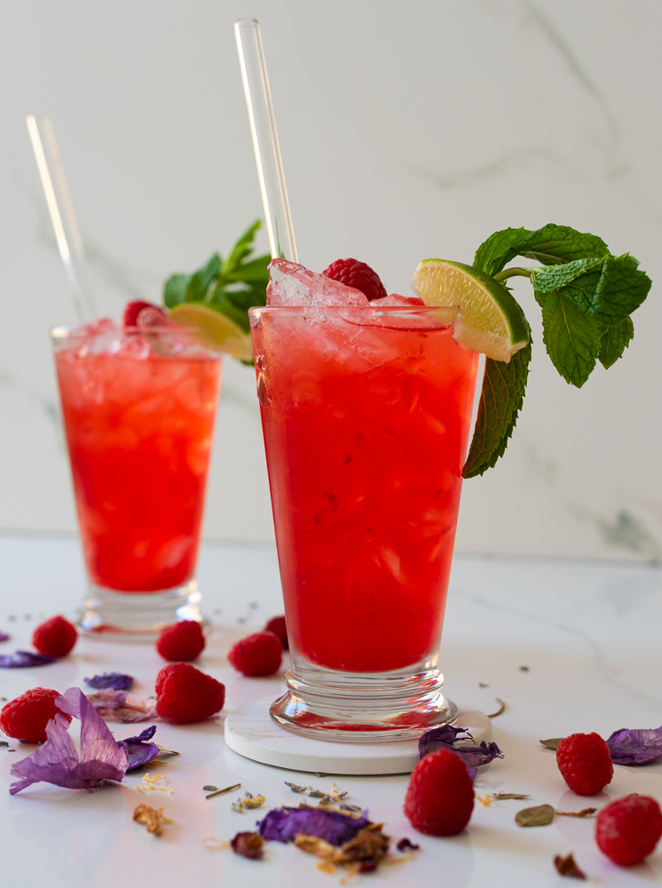 two glasses of lavender mojito mocktail with lime and mint and flowers