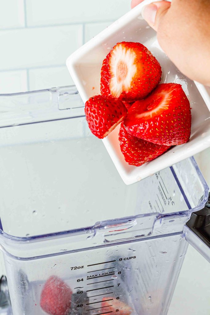 Pouring strawberries into blender 