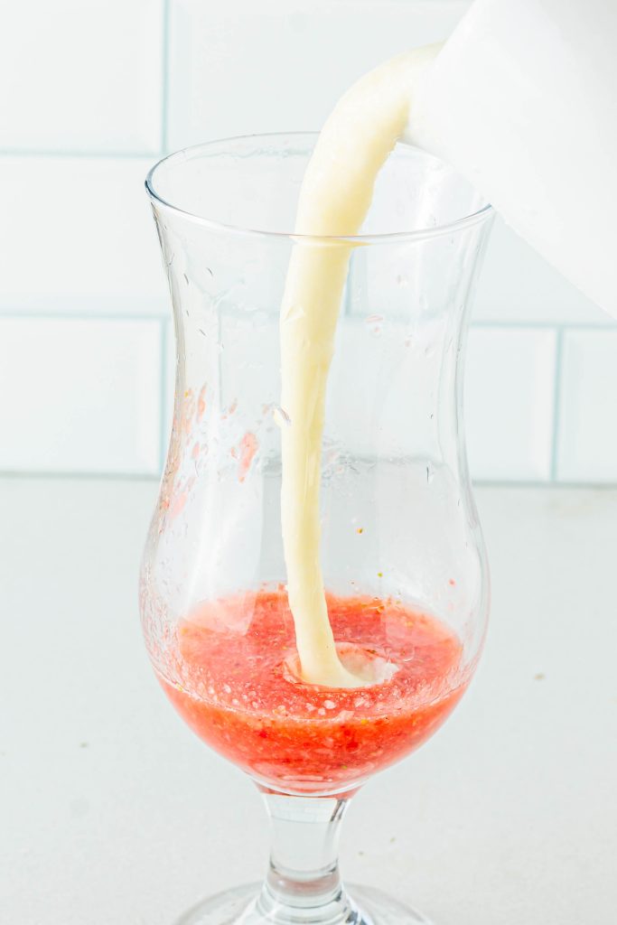 Pour Pina Colada mixture into the glass of strawberry puree