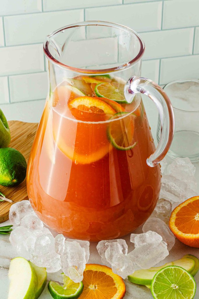 Pitcher of holiday fruit punch with slices of citrus fruit and apples