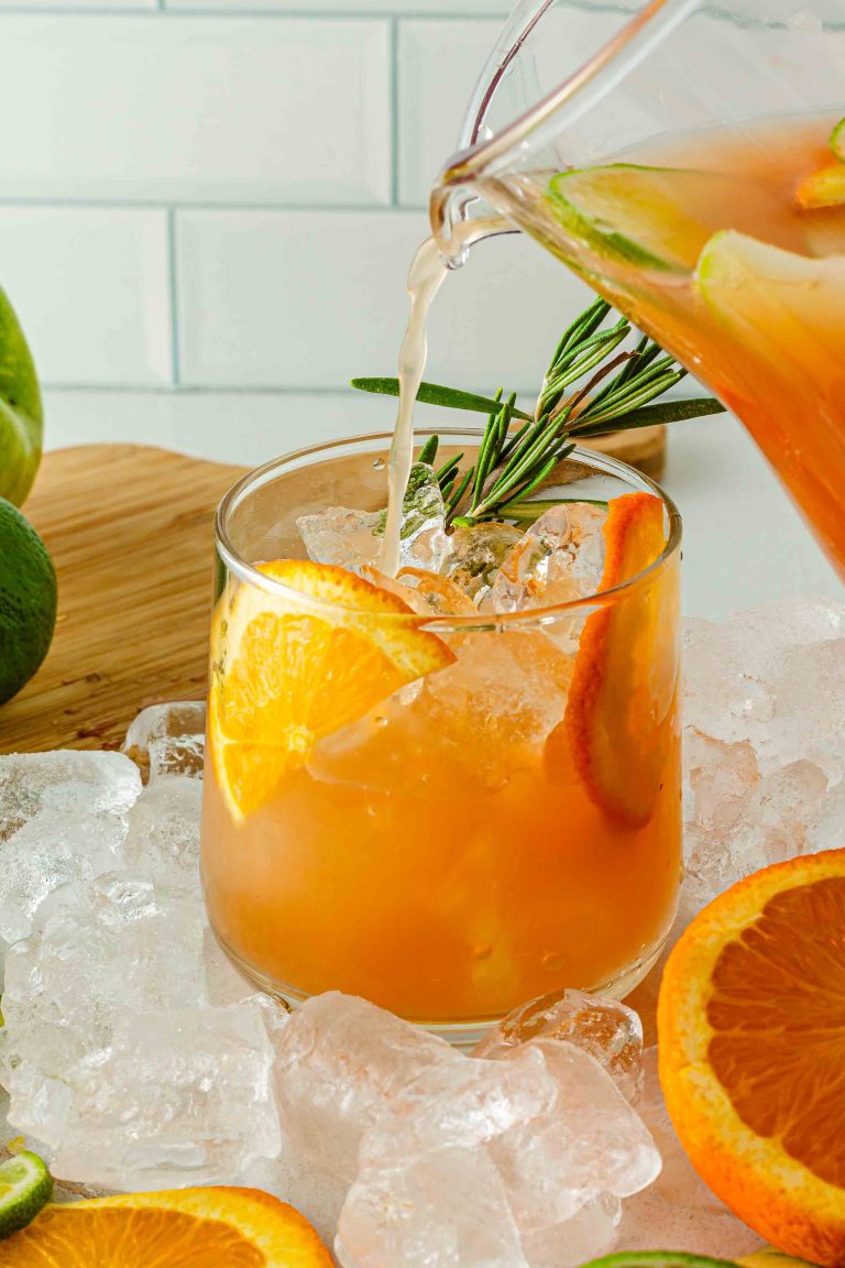 Glass of holiday fruit punch with sliced orange and rosemary