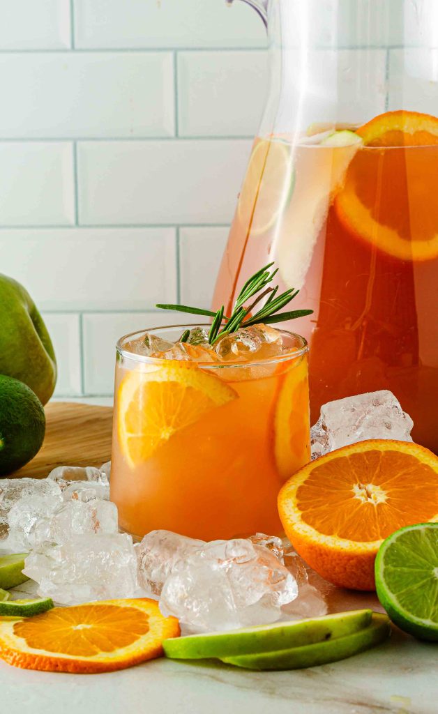 glass of non-alcoholic fruit punch with a pitcher behind it