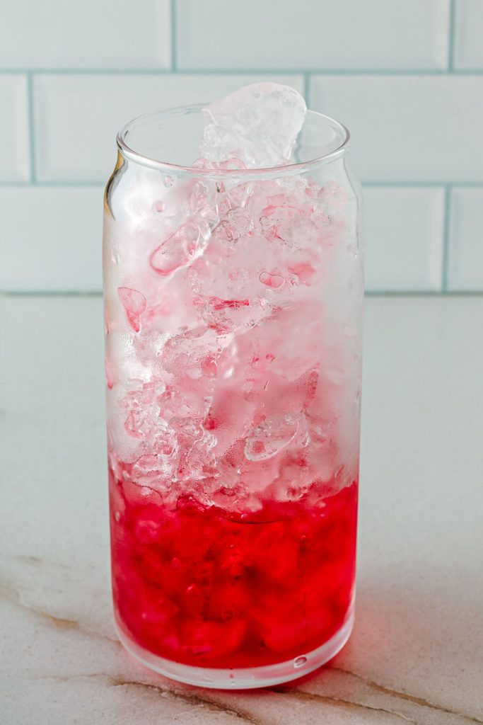 Adding cranberry juice to glass of ice