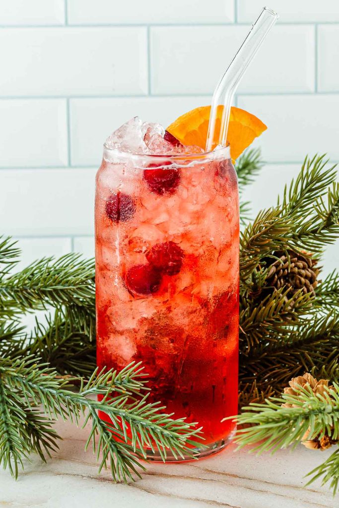 Tall glass of cranberry mocktail with holiday greens