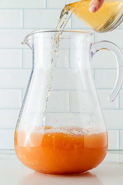 Adding sparkling apple juice to pitcher of holiday punch recipe
