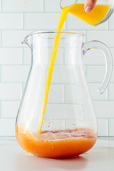Adding orange juice to pitcher of Christmas punch recipe