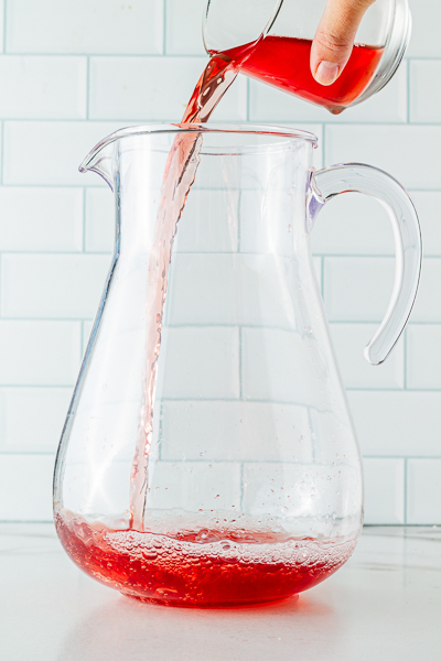 Pouring Cranberry juice into pitcher for holiday punch 