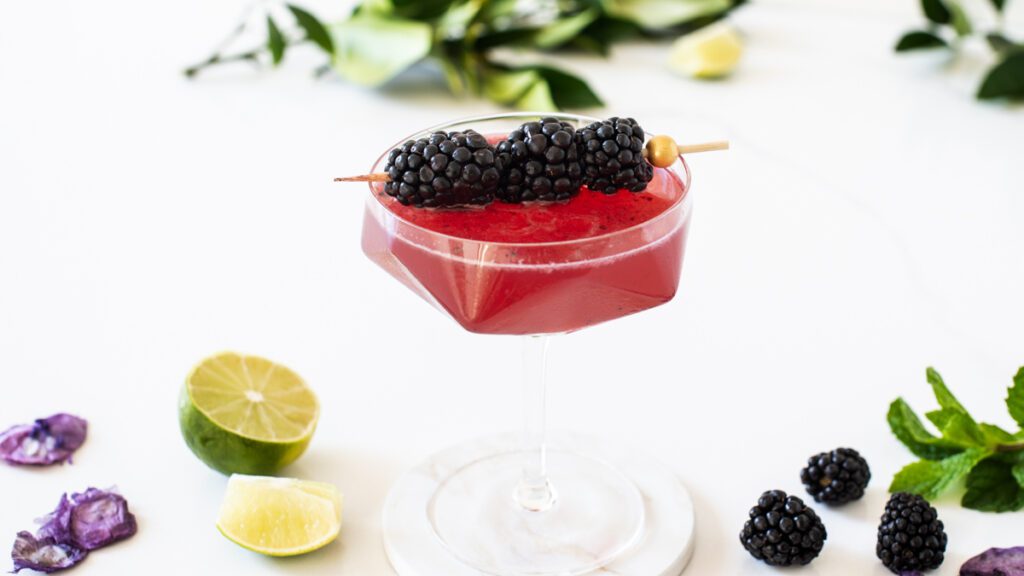 Blackberry Mocktail in coupe glass surrounded by fruit
