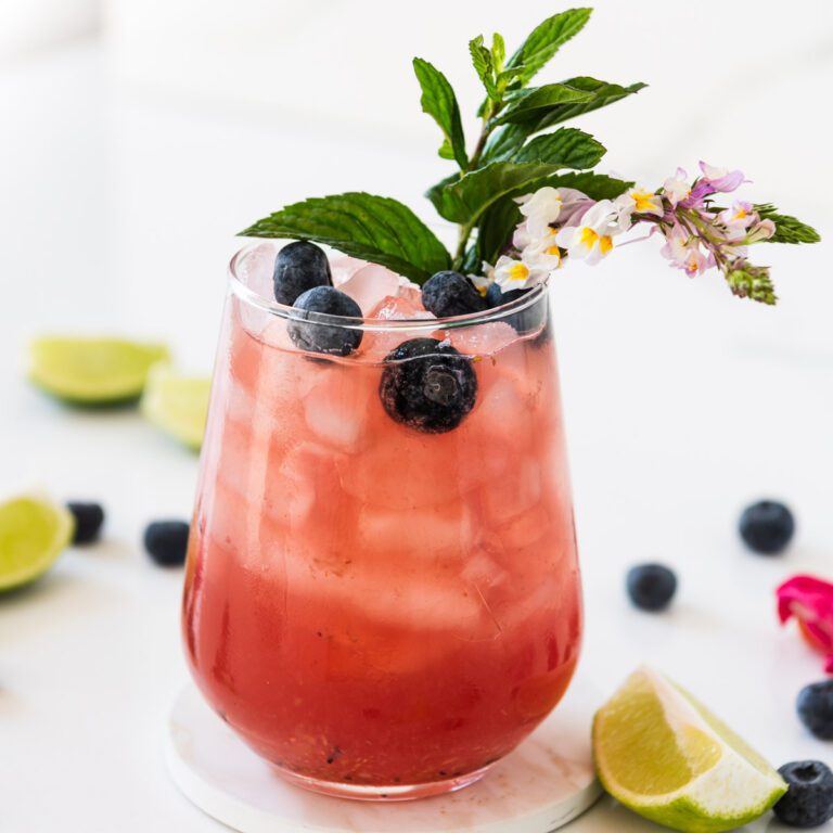Glass of Blueberry Mojito Mocktail with fresh mint and edible flowers
