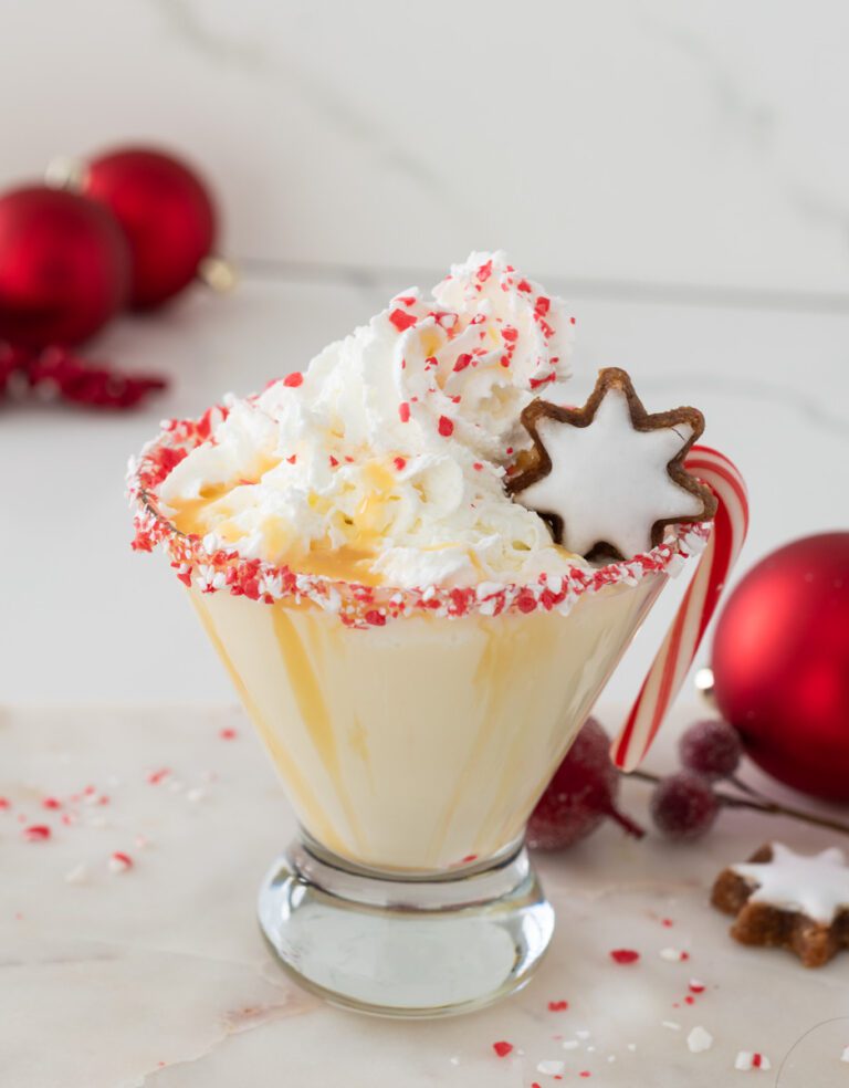 Creamy Peppermint White Chocolate Mocktail topped with whipped cream and served with mini gingerbread cookies—holiday drink idea.