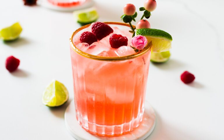 glass of raspberry pink mojito mocktail with fresh mint and lime