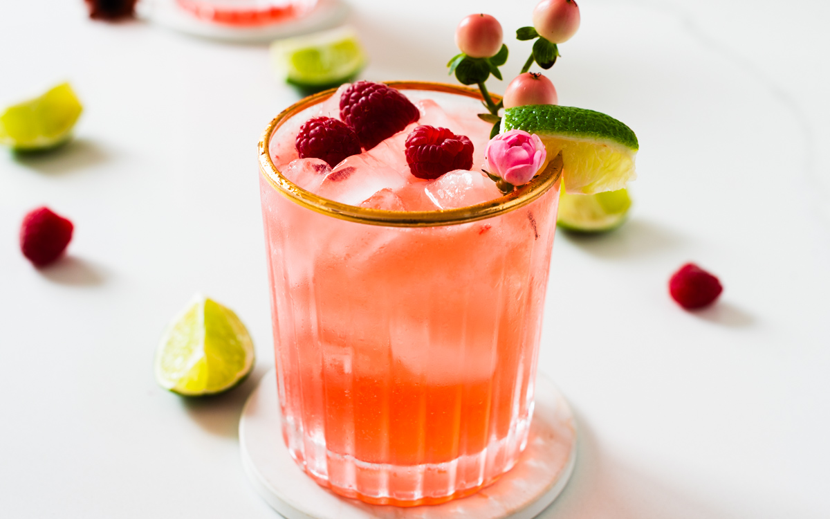 glass of raspberry pink mojito mocktail with fresh mint and lime