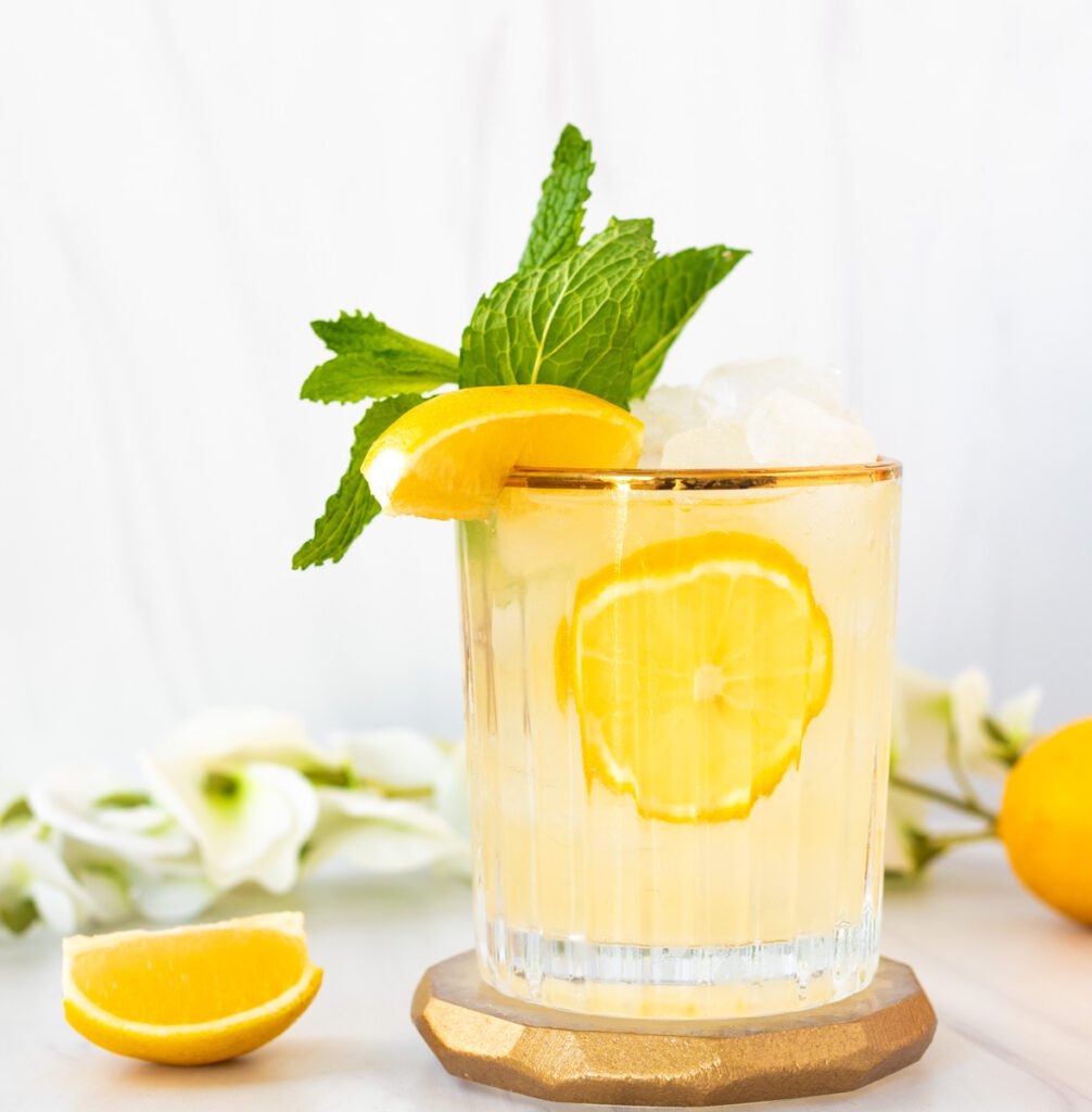glass of lemon mojito mocktail with bright fresh yellow lemons