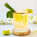 glass of coconut mocktail with fresh limes and mint
