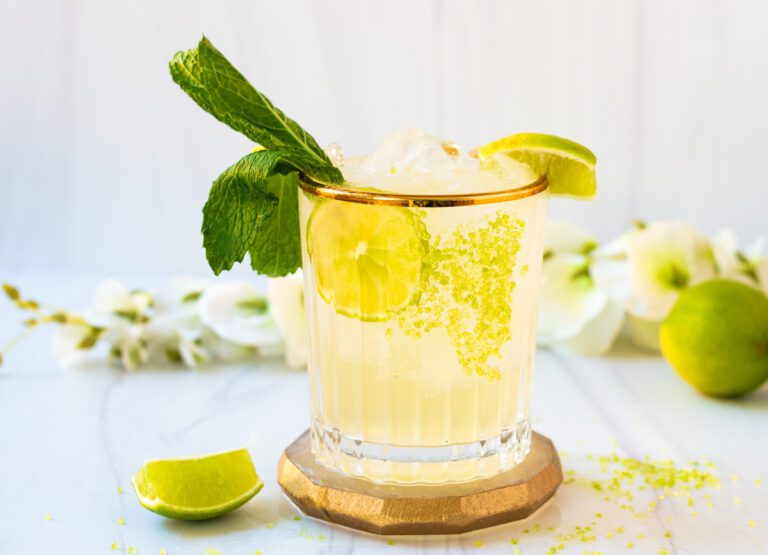 glass of coconut mocktail with fresh limes and mint