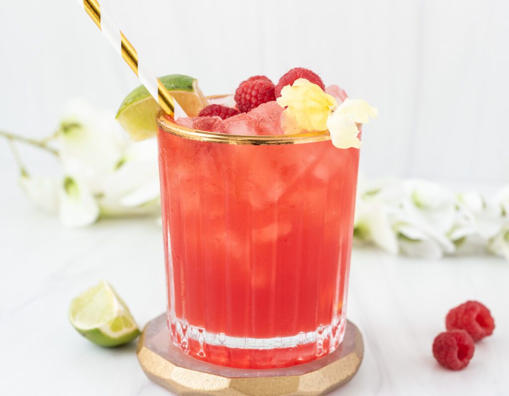 Glass of bright pink raspberry margarita mocktail with flowers 