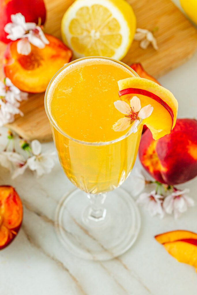 close up of golden peach mocktail with fresh edible white flowers