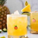 glass of non alcoholic pineapple margarita with chunks of fresh pineapple