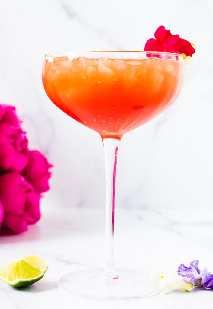 raspberry mocktail in coupe glass with edible pink flowers