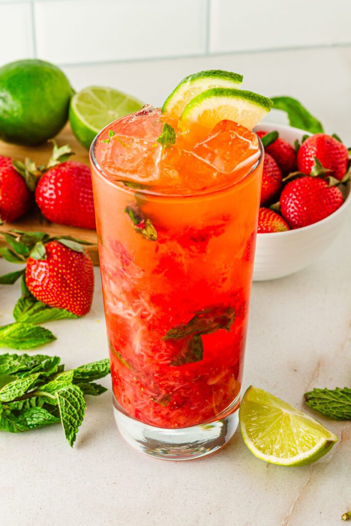Non-alcoholic strawberry mojito in glass surrounded by fresh strawberry's