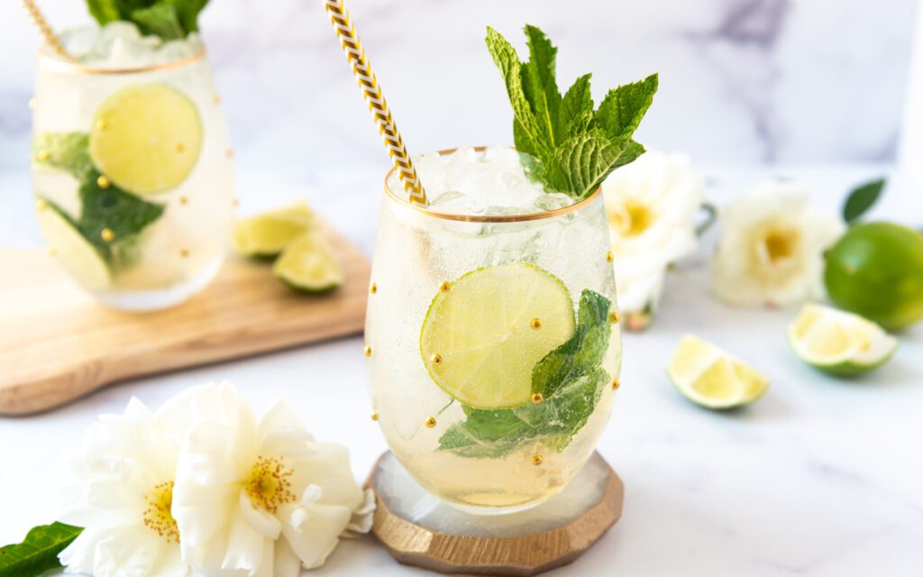 Two glasses of Italian inspired Hugo Spritz Mocktail with white flowers, ice and limes