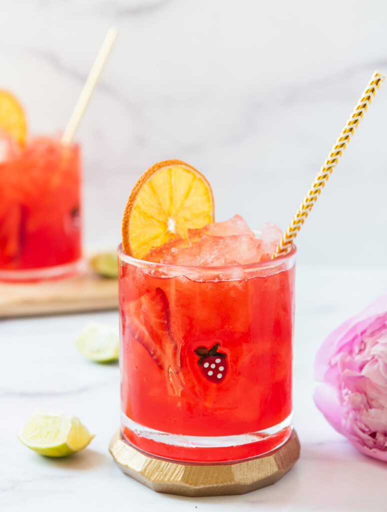 cold glass of strawberry virgin margarita with sliced orange