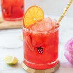 glass of bright pink strawberry virgin margarita with an orange slice