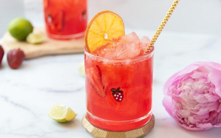 glass of bright pink strawberry virgin margarita with an orange slice