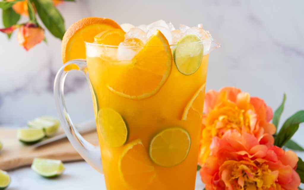 pitcher of tropical virgin margarita with sliced citrus and flowers