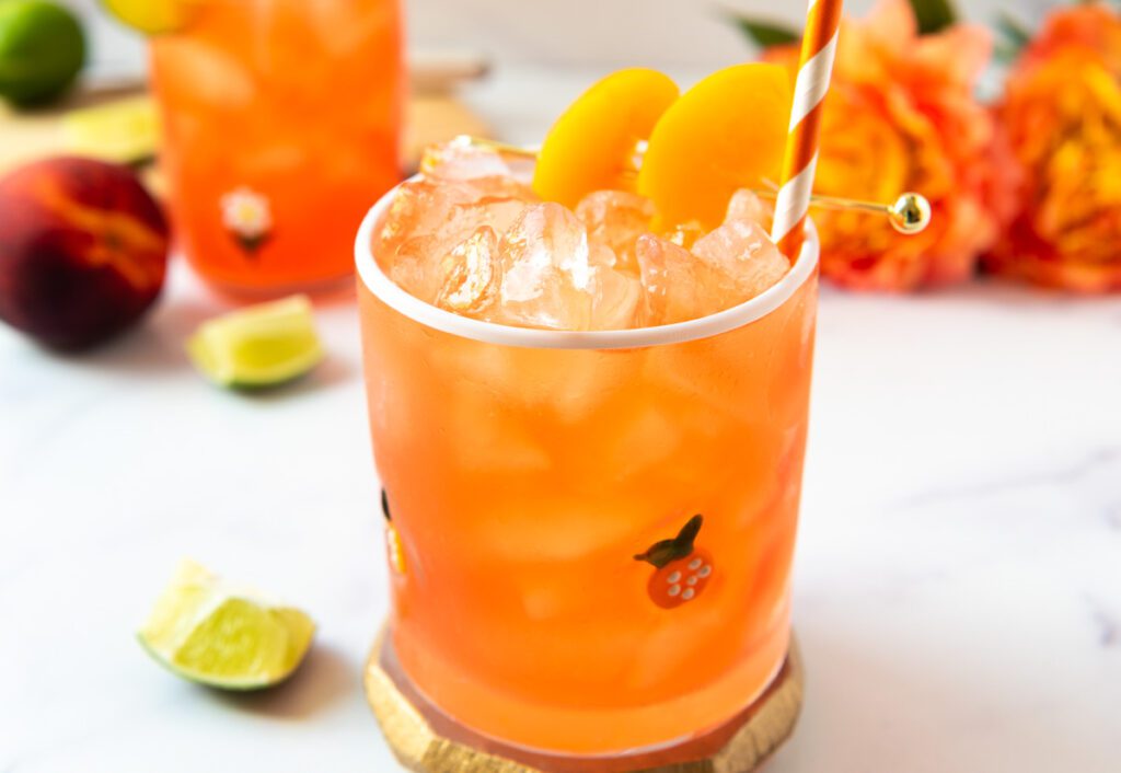 glass of peach virgin margarita with fresh lime and orange flowers