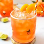 glass of peach virgin margarita with fresh lime and orange flowers