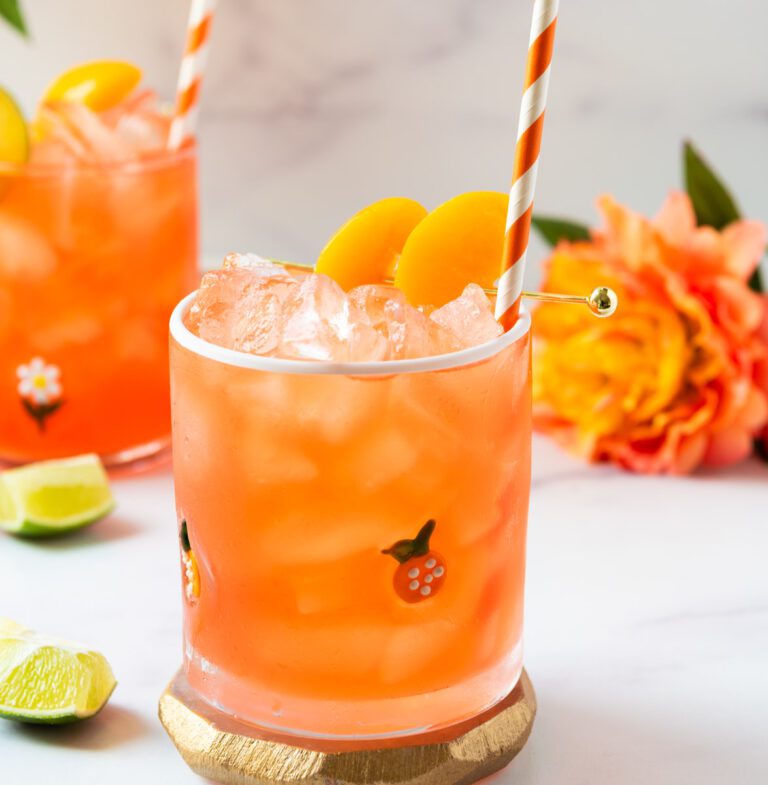 two glasses of peach virgin margarita with orange and white straws