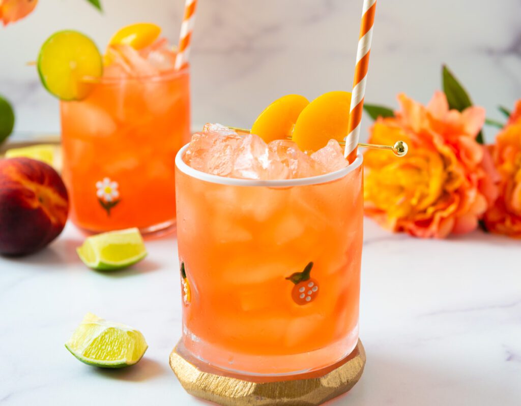 Peach Virgin Margarita with sliced peaches and limes and orange flowers