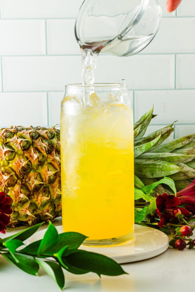 adding pineapple juice to glass