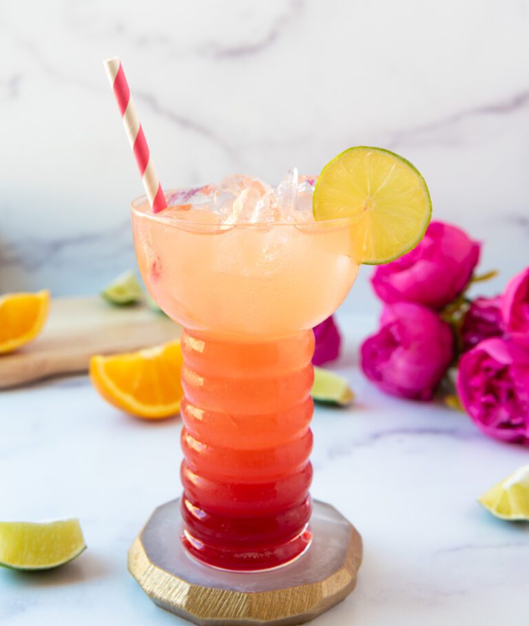 glass of strawberry pineapple spritz with pink flowers and pink and white straw