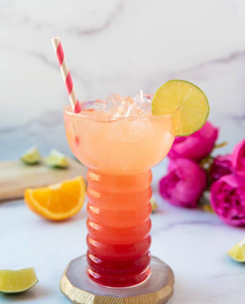 layered strawberry pineapple sunrise spritz with pink dn white straw